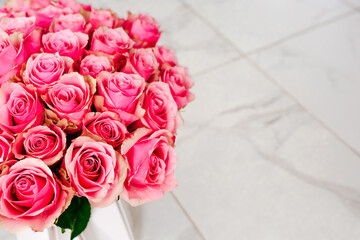 Beautiful pink roses arranged elegantly on a white table in a bright indoor space