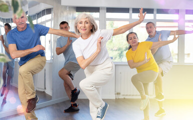 Elderly woman dances energetic modern dances in group in studio