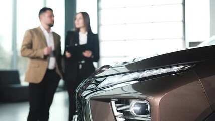 A female car dealer dressed in business attire consults a man about buying a vehicle in a modern showroom. Concept professional car consultation.