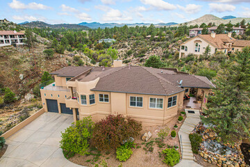 Aerial view of a large house on a hill with mountains behind