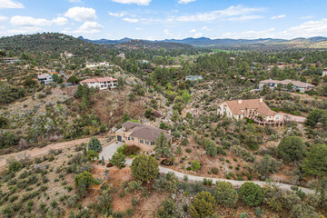 Aerial view shows a house on a hill, amid lush trees and greenery