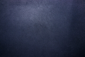 A close-up view of a textured navy blue leather background, highlighting its smooth surface and...