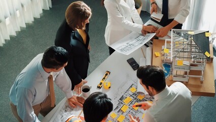 Top view of skilled architect engineer team inspect house model while project manager hold...