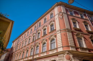 Graz, Austria – July 22, 2025: Historic residential buildings and storefronts with stucco façades and traditional wooden windows in the Old Town district of Graz under a clear summer sky.
