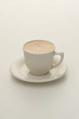 White cup of cappuccino with foam on a white background