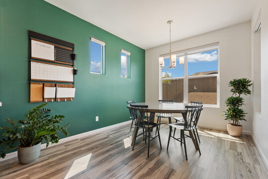 A dining room with a table and chairs against a green wall