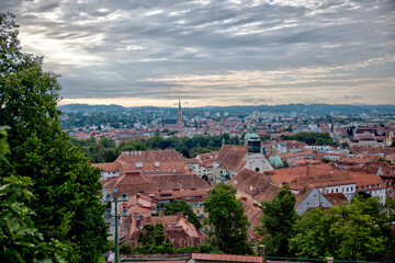 Naklejka premium Graz, Austria – July 22, 2025: A view of the city’s rooftops and skyline from the Schlossberg hill, offering a picturesque overlook of the urban landscape below. 