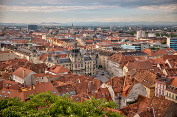 Obraz premium Graz, Austria – July 22, 2025: A view of the city’s rooftops and skyline from the Schlossberg hill, offering a picturesque overlook of the urban landscape below. 