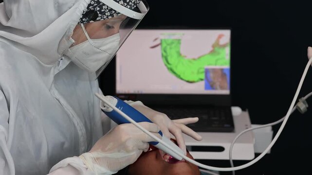 Dentist using an intraoral scanner to create a digital 3D impression of a patient's teeth in a modern dental clinic with CAD/CAM technology.