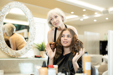 Elderly woman hairdresser master does discusses with client length of hair, shape of haircut. Casual hairstyle, length reduction