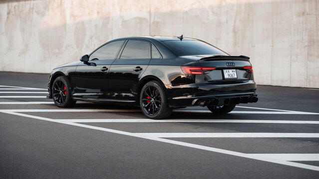 Black Audi A4 on urban road. Three quarter rear view of compact executive sedan near concrete retaining wall of highway ramp. Ukraine - November 03 2024