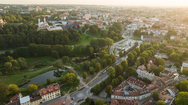 An aerial cityscape captures a European city at sunset, showcasing historic architecture and lush parks. Vilnius, Lithuania