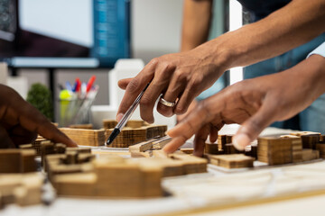 Obraz premium Close up of engineers uniting forces for residential project layout with 3D models for infrastructure growth initiative, real estate team creates housing blueprints for site preparation.