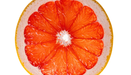 A cross-section of a ripe, juicy grapefruit, with vibrant red pulp and white pith, against a dark background