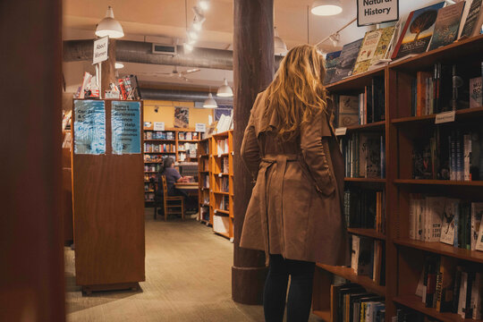 woman reads books, graduate studies in cozy bookstore, quiet evening exploring vintage novels