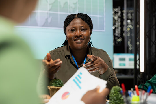 African american finance analyst shows data analytics in briefing meeting, presenting the business situation with the investors group. Woman CEO discuss changes with shareholders.