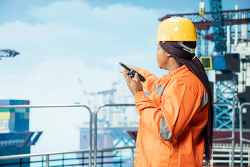 Drilling rig technician uses two way radio to communicate with logistics crew coworkers. Woman...