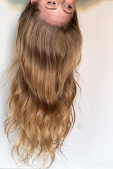 Naklejka premium A woman with beautifully long blonde hair is currently upside down