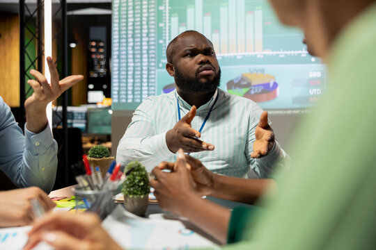 African american worried CEO addressing business issues in a late night meeting, discussing about improvement and development with his team. Aligning activity with company objectives.