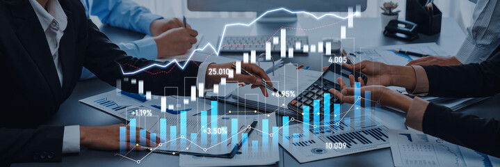 A business team collaborates in a modern office setting, analyzing financial data and stock trends using graphs and calculators, showcasing teamwork and strategic planning. Scalp