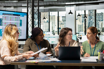 Ambitious and goals oriented staff members reviewing corporate reports and graphs, working in synergy to achieve professional development in a modern work environment. Productivity.