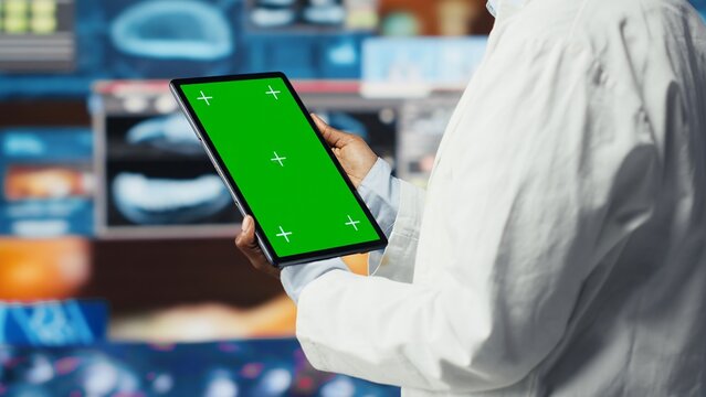 Chroma key tablet used by healthcare expert looking at MRI data analytics. African american scientist in medical lab reading health data with mockup device software, camera B