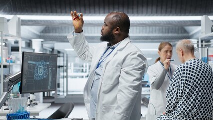 Black medic recording pharmacology data with artificial intelligence, analyzing patient reaction for a new drug testing with machine learning and neural networks. Medical progress. Camera B.