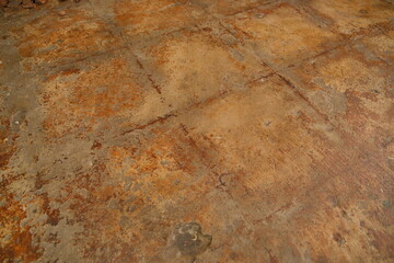 Distressed concrete floor displaying a weathered grunge surface with oxidized brown and orange rust-like textures, creating an abstract industrial background