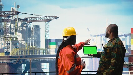 Chroma key tablet used by soldier on offshore platform deck talking with technician. African american naval unit guards drilling rig against terrorist threat using green screen mockup device, © DC Studio