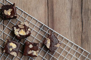 Delicious homemade chocolate brownies topped with almond slices arranged on a cooling rack over a rustic wooden background for dessert lovers and baking enthusiasts.