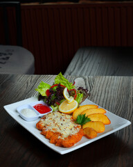 Delicious Chicken Steak with Potato Wedges and Fresh Salad on Wooden Table