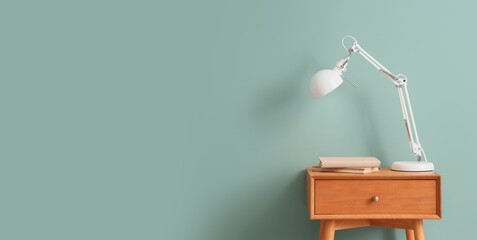 Lamp with books on table near light blue wall. Banner for design