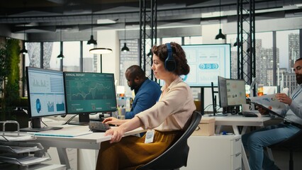 Office administrator uses focus music on headset to solve tasks, monitoring performance metrics at...