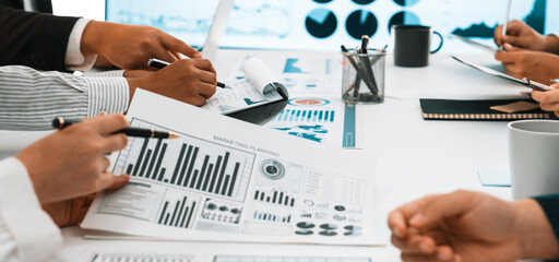 A diverse business team collaborates in a modern office setting, reviewing financial data reports and visualizations to foster informed decision-making and strategic planning. SACTR