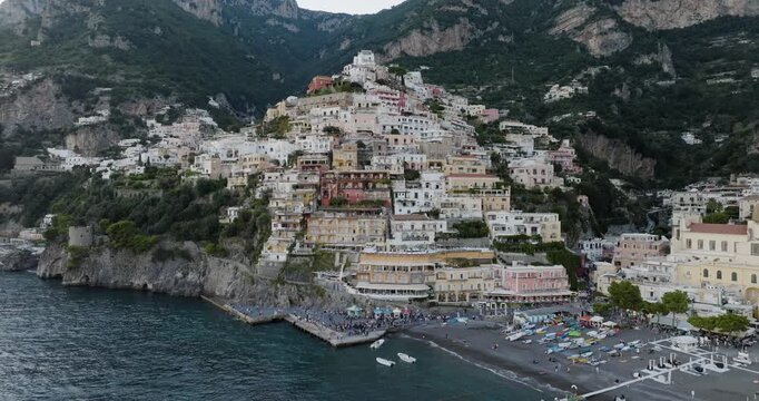Aerial view of Positano's colorful buildings cascading down to the dark beach and turquoise sea, creating a vibrant contrast, Positano, Amalfi Coast, Italy.
