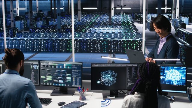 Software developers cooperating in data center, reviewing AI diagnostics on computer. IT staff members discussing in server room, optimizing machine learning systems, camera A - Powered by Adobe