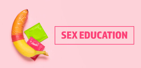 Condoms and banana on pink background. Sex education