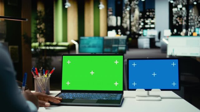 Young male worker checking green screen and blue screen on gadgets, engaged in budgeting or financial projections after hours. Office employee solving important tasks with tech. Camera A.