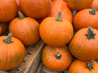 Vibrant orange pumpkins stacked together on wooden crates, showcasing their round shapes and textured surfaces, perfect for autumn decoration and seasonal harvest themes