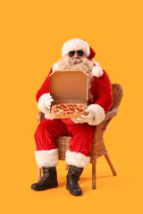Cool Santa Claus with tasty pizza in armchair on yellow background