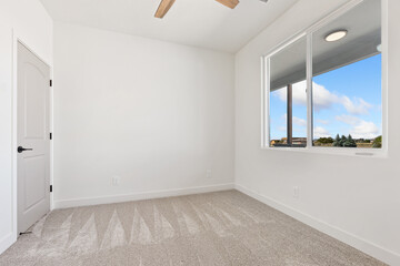 A vacant bedroom space equipped with two windows and a ceiling fan