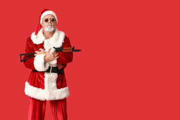 Santa Claus in sunglasses with assault rifle on red background