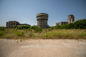 Abandoned distillery tower in Italy – circular industrial building with glass dome, steel beams, panoramic windows, decaying factory interior, urban exploration, post-industrial architecture
