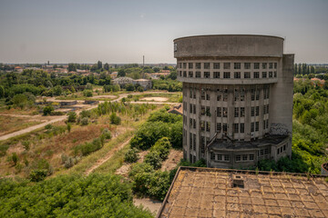 Abandoned distillery tower in Italy – circular industrial building with glass dome, steel beams, panoramic windows, decaying factory interior, urban exploration, post-industrial architecture