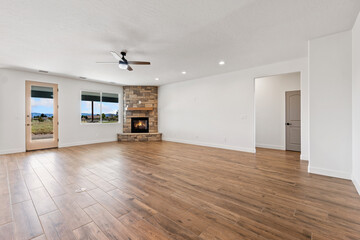 An empty living room with hardwood floors and a cozy fireplace