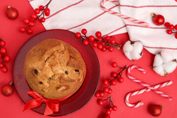 Plate with tasty Panettone and Christmas decor on red background