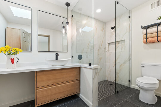 A bathroom that features a toilet, sink, mirror, and a walkin shower