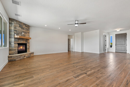 A spacious, vacant room with hardwood flooring and a ceiling fan