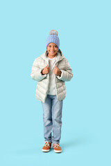 Cute little happy African-American boy in winter clothes on blue background