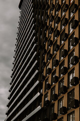 A fragment of a modern architectural facade, residential building against a cloudy sky. The...